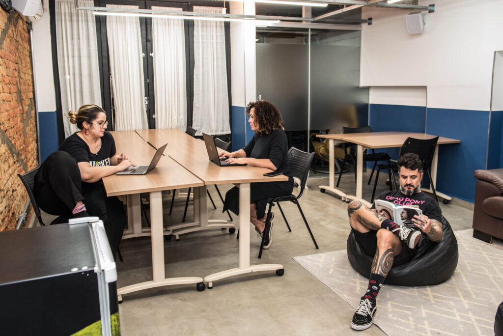 Imagem mostra 3 pessoas trabalhando em um espaço de coworking