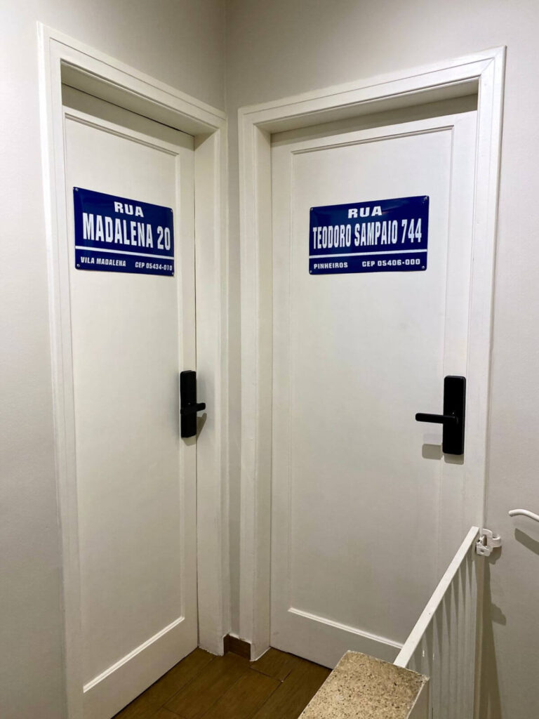 Imagem mostra placas decorativas azuis na porta de cada quarto da Blocktime Spaces