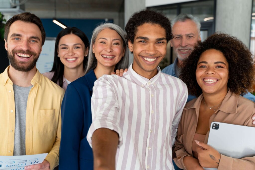 A imagem mostra 6 pessoas sorrindo para a foto, de perfis e idades diferentes. A Ideia é mostrar a diversidade do mercado de trabalho.