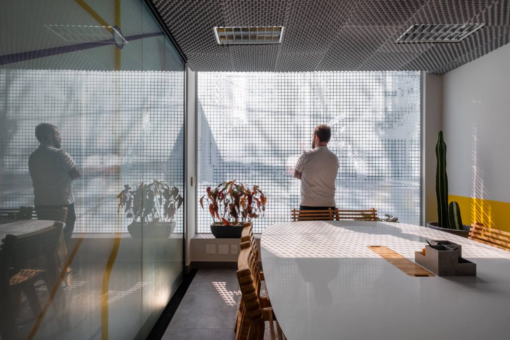 Imagem mostra homem dentro de uma sala da Blocktime Coworking. Ele está de costas pra imagem, olhando a rua, numa sala de vidro.