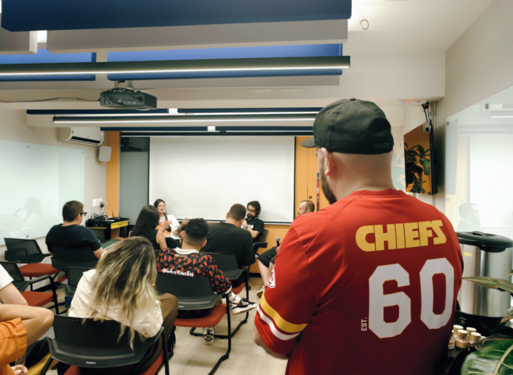 Imagem mostra espaço de eventos da Blocktime Heroes, onde as pessoas assistem a um painel. O ambiente é ideal para ter mais foco no trabalho e realizar um evento com toda estrutura necessária.