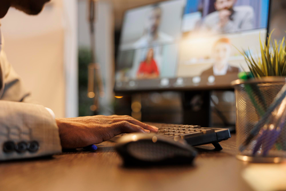 Profissional trabalhando no computador durante uma reunião virtual com a equipe.