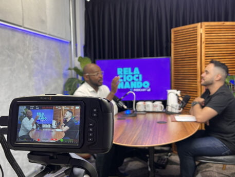 Programa com dois homens sendo gravado na sala de podcasts do Blocktime Coworking.