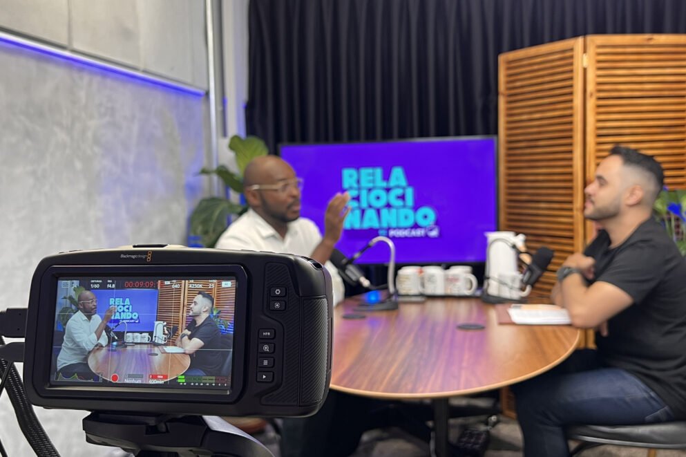 Programa com dois homens sendo gravado na sala de podcasts do Blocktime Coworking.