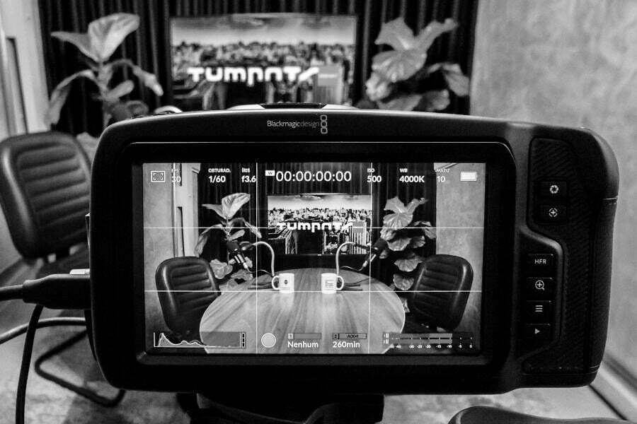 Foto em preto e branco de uma câmera gravando a sala de podcasts.