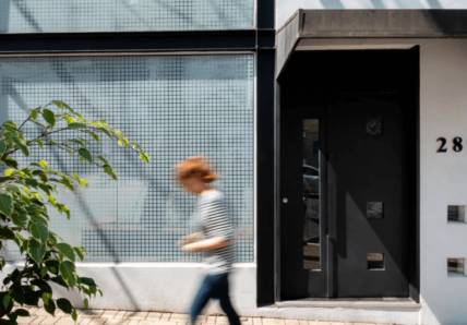 Imagem mostra moça caminhando, passando em frente de um coworking