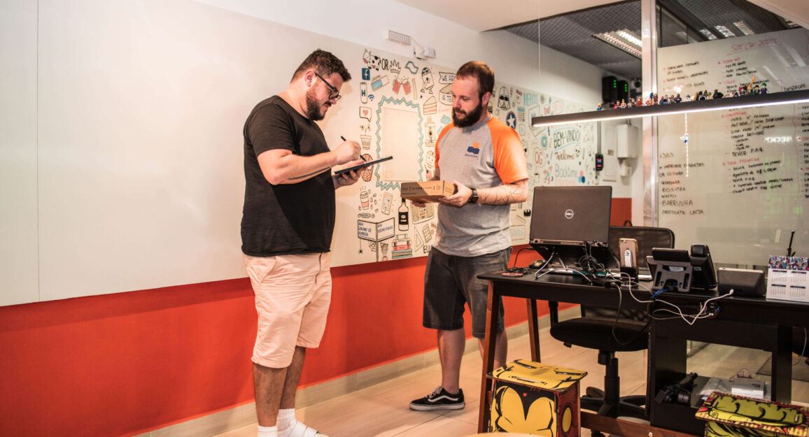 Imagem mostra um homem branco recebendo suas correspondências fiscais na recepção da Blocktime Coworking