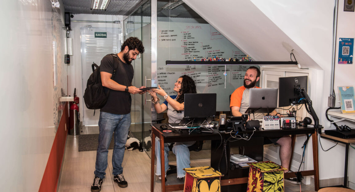 A imagem mostra a recepção da Blocktime Coworking, com uma mulher atendendo um cliente e o recebendo na unidade