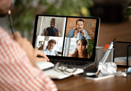 Imagem mostra líder conectado com o time virtualmente em uma reunião. Na tela do computador estão as imagens de cada colaborador.