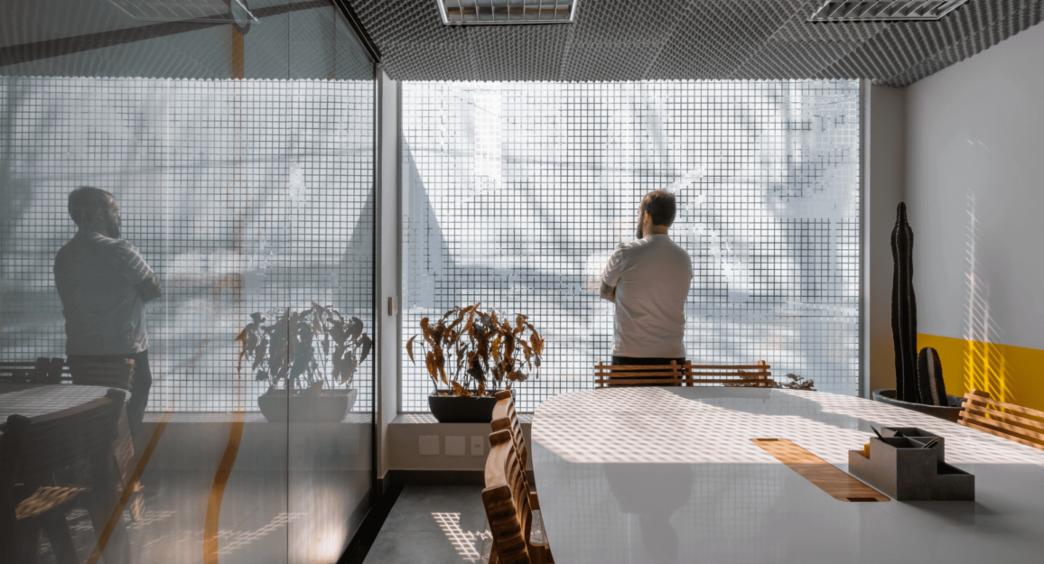 Imagem mostra homem de costas em um escritório, sala de reunião, da Blocktime Coworking.