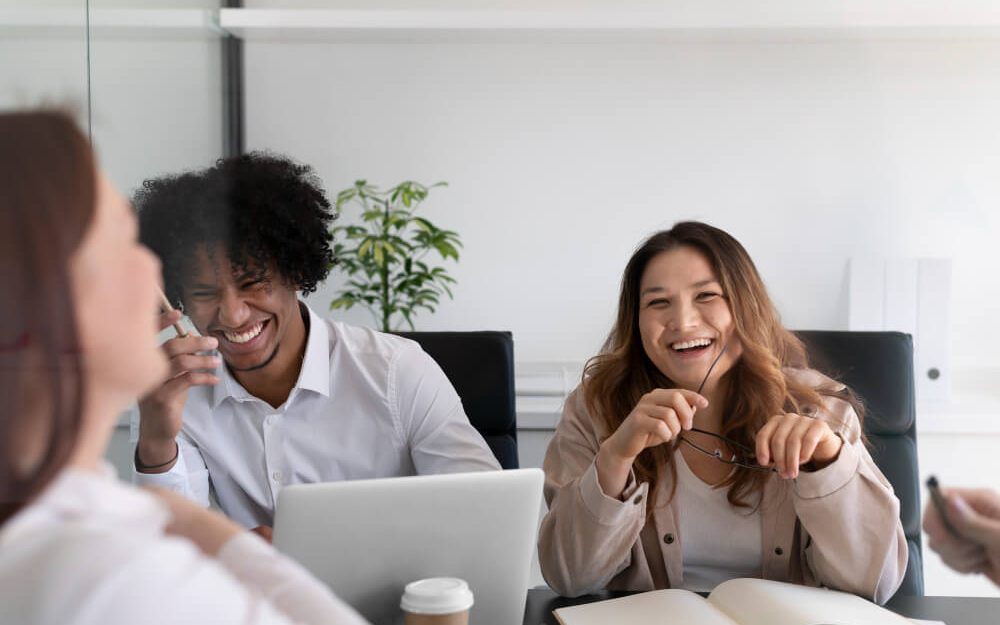 Imagem mostra pessoas em ambiente de trabalho sorrindo enquanto conversam