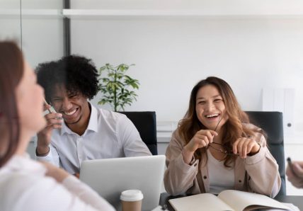 Imagem mostra pessoas em ambiente de trabalho sorrindo enquanto conversam