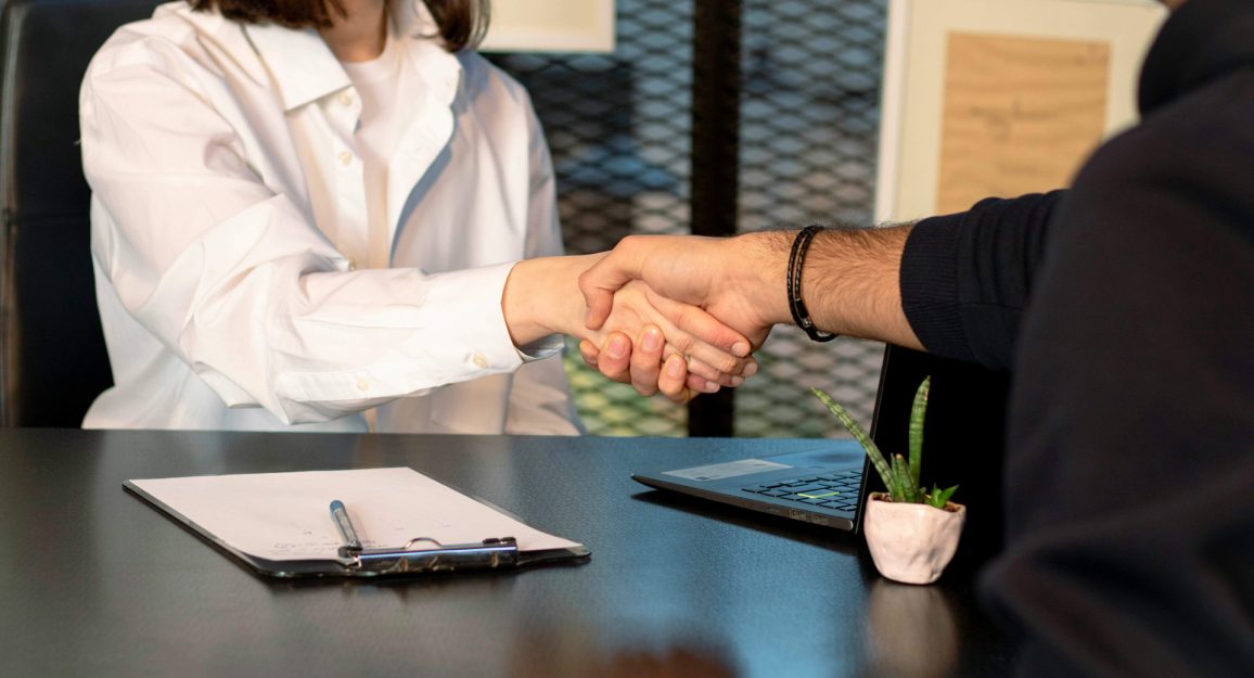 Imagem mostra duas pessoas fazendo um aperto de mãos. Na imagem mostra uma mulher e um homem, como se estivesse fechando um negócio.
