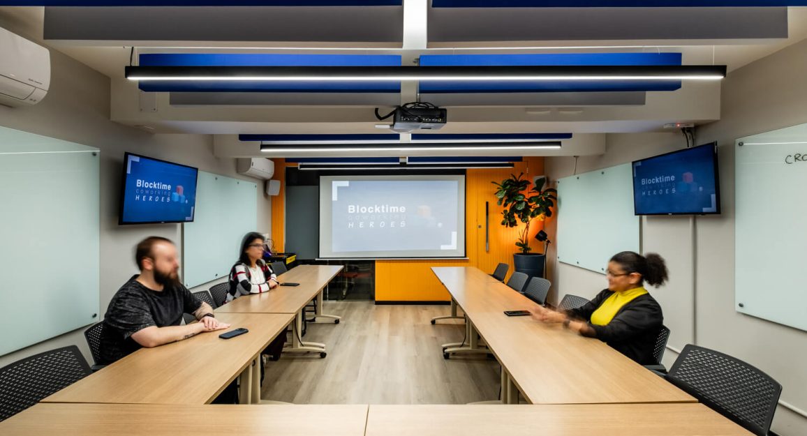Equipe reunida em sala da Blocktime Coworking Heroes, em Pinheiros, São Paulo, para encontro presencial no modelo de trabalho híbrido.